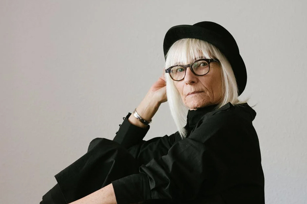 a portrait of a woman in black with gray hair wearing glasses